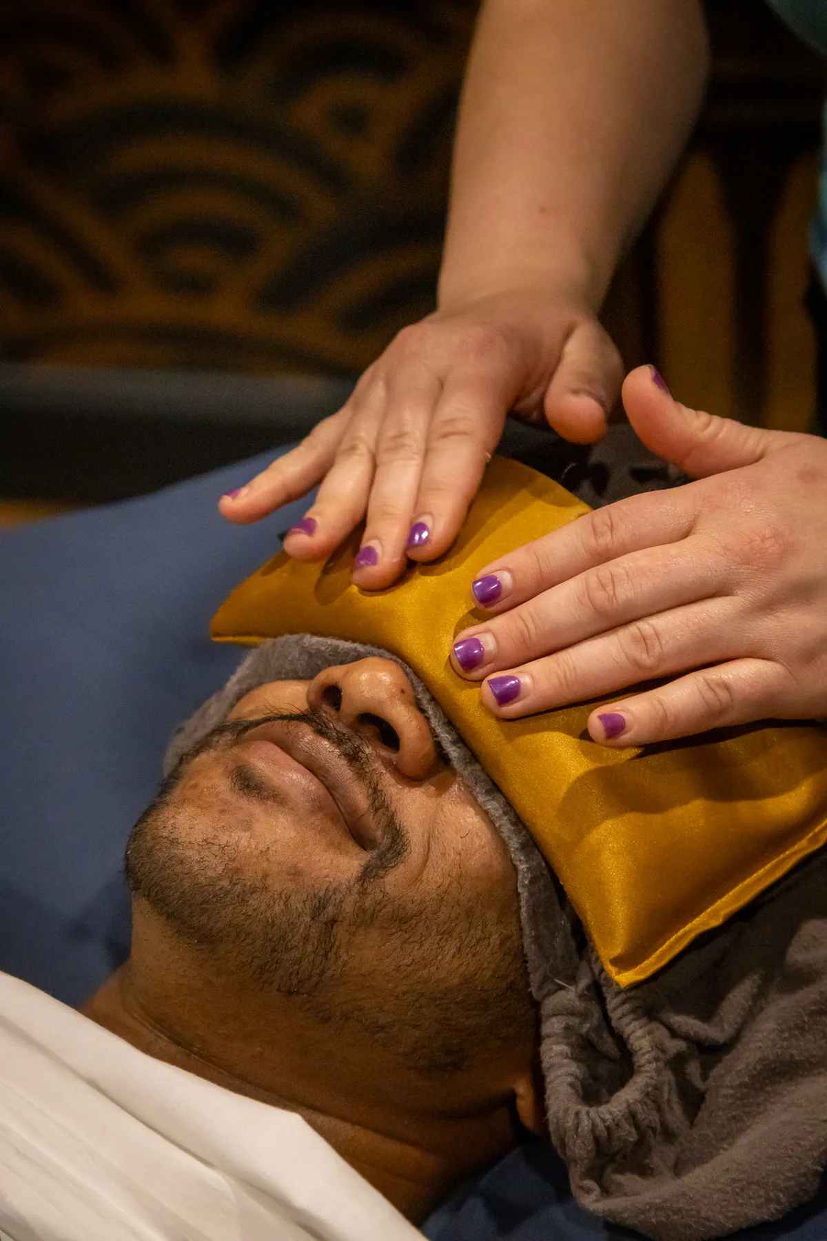 Client resting with a warm eye pillow during a treatment at Auroraflow